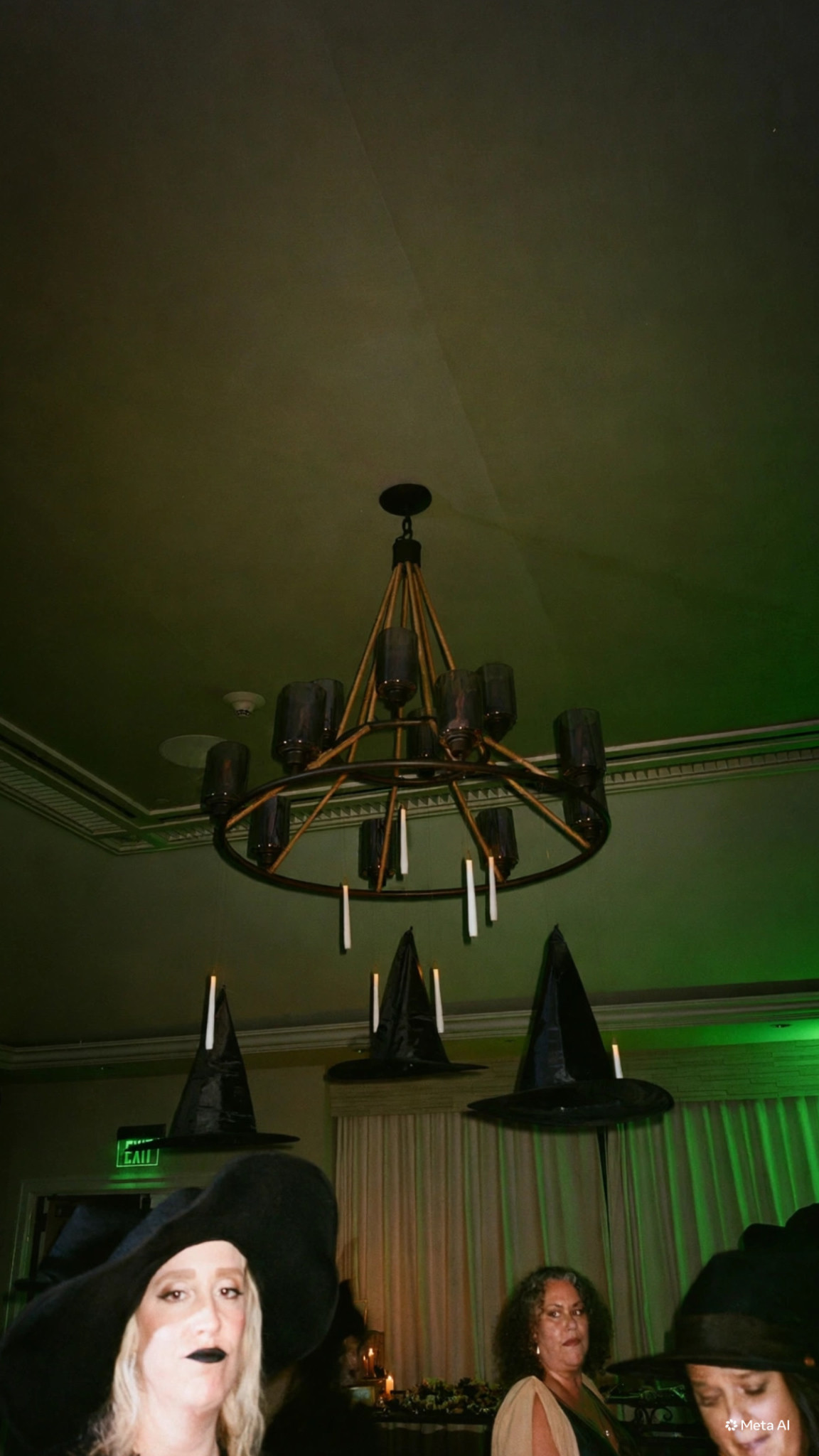 Suspended witch hats and candles beneath a chandelier at Estancia's Halloween party.