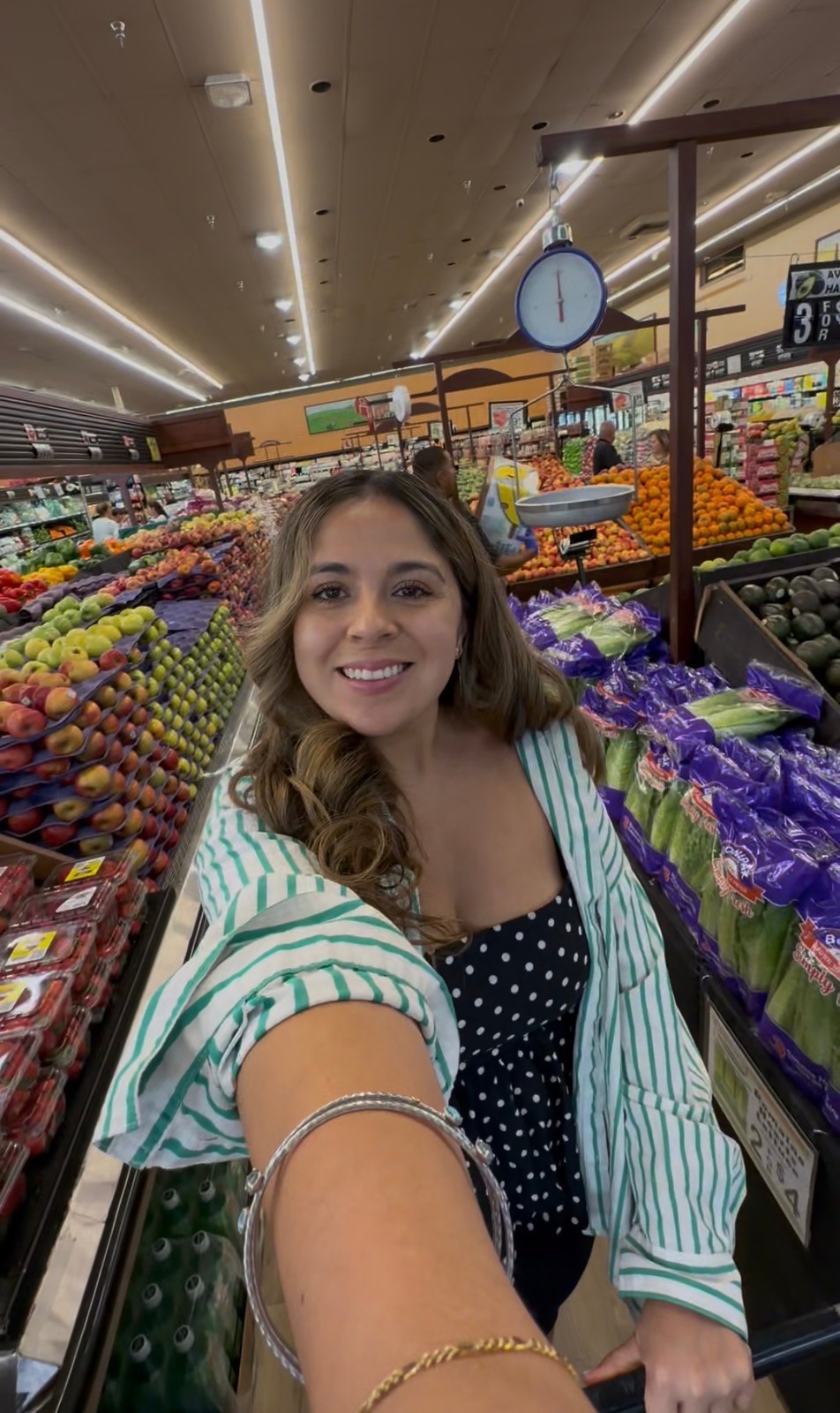 Giselle in the Carnival Chula Vista produce aisle, surrounded by displays of fruit and vegetables.