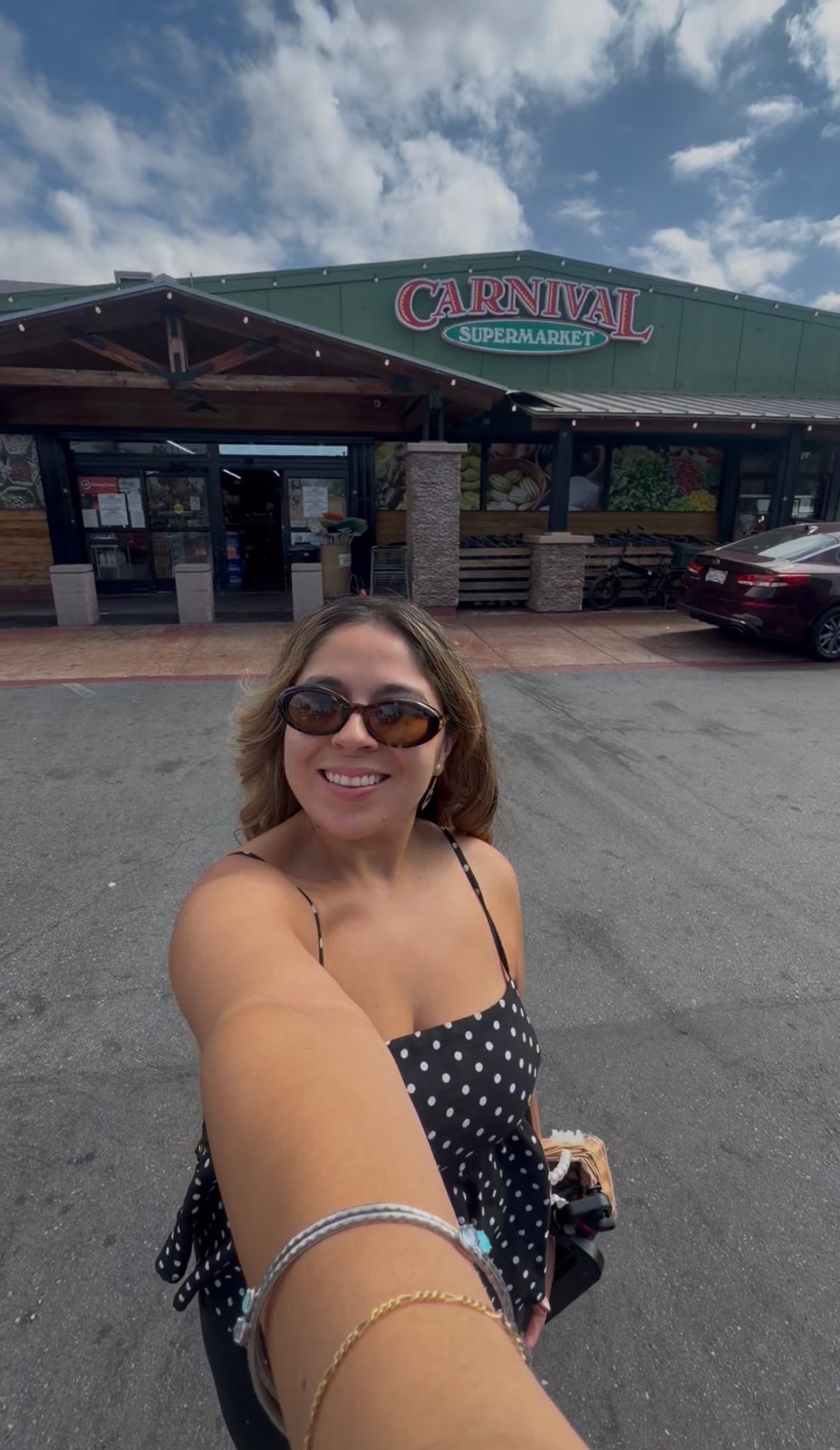 Giselle outside Carnival Supermarket in National City, with the store sign behind her.