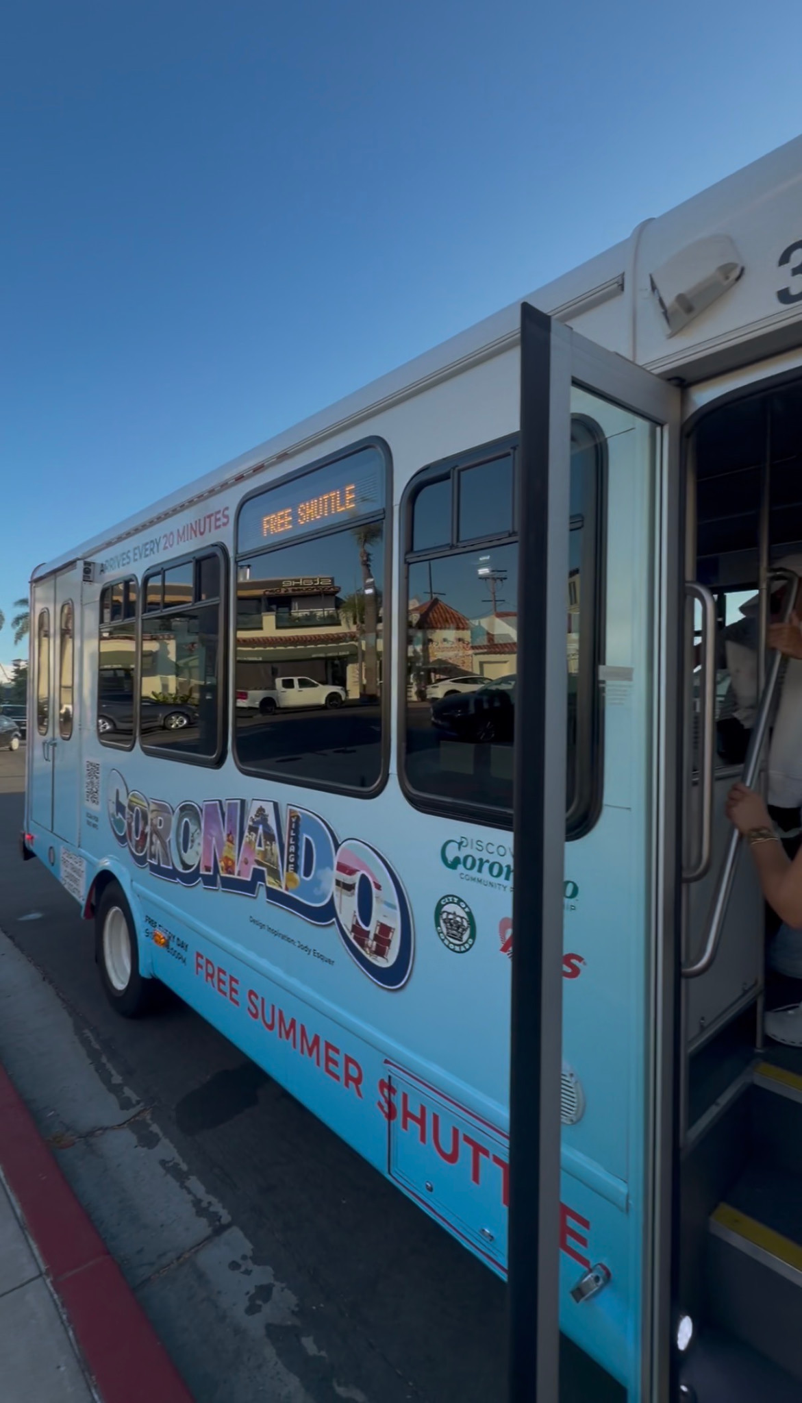 A blue-and-white Coronado bus marked Free Summer Shuttle, with its door open.