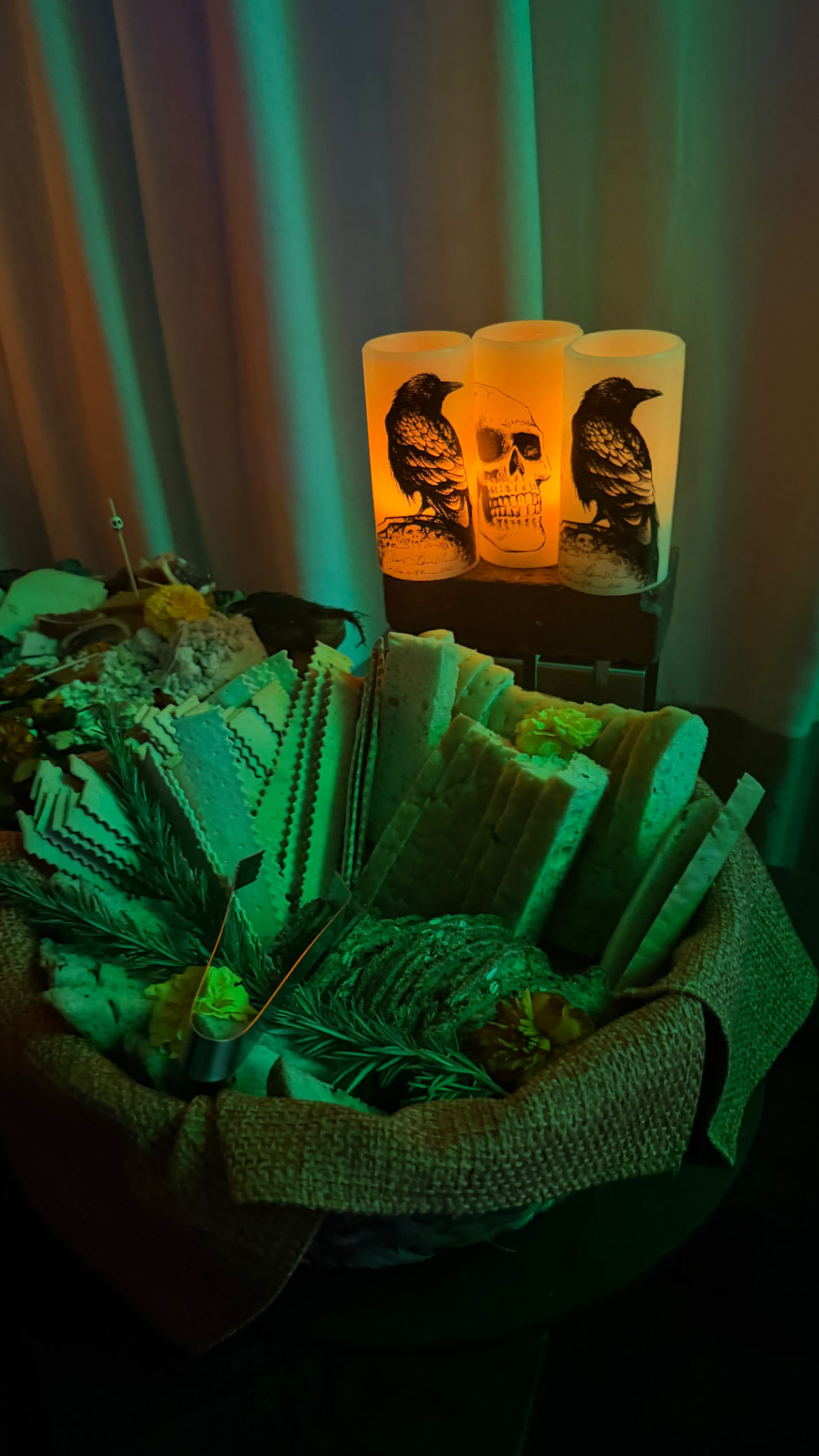 Bread and crackers beneath glowing raven and skull candles at Estancia's Halloween party.