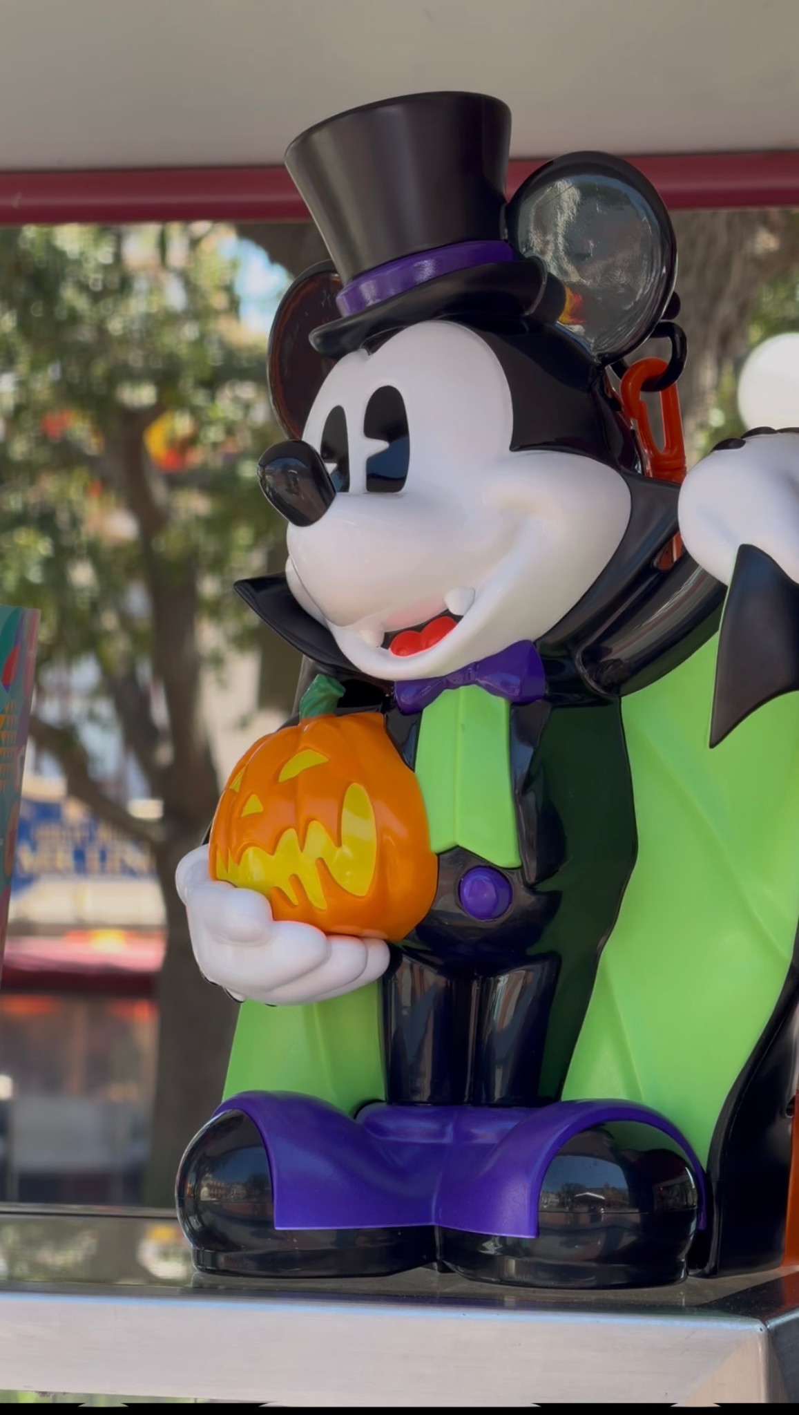 A vampire Mickey Mouse bucket with a black top hat, green cape and orange jack-o’-lantern.