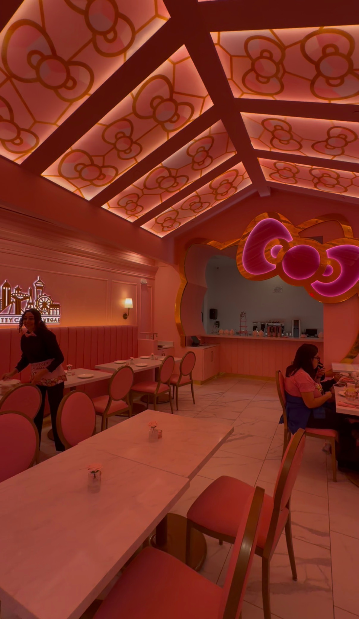 Pink Bow Room dining area with bow-patterned ceiling panels and a large Hello Kitty-shaped opening.