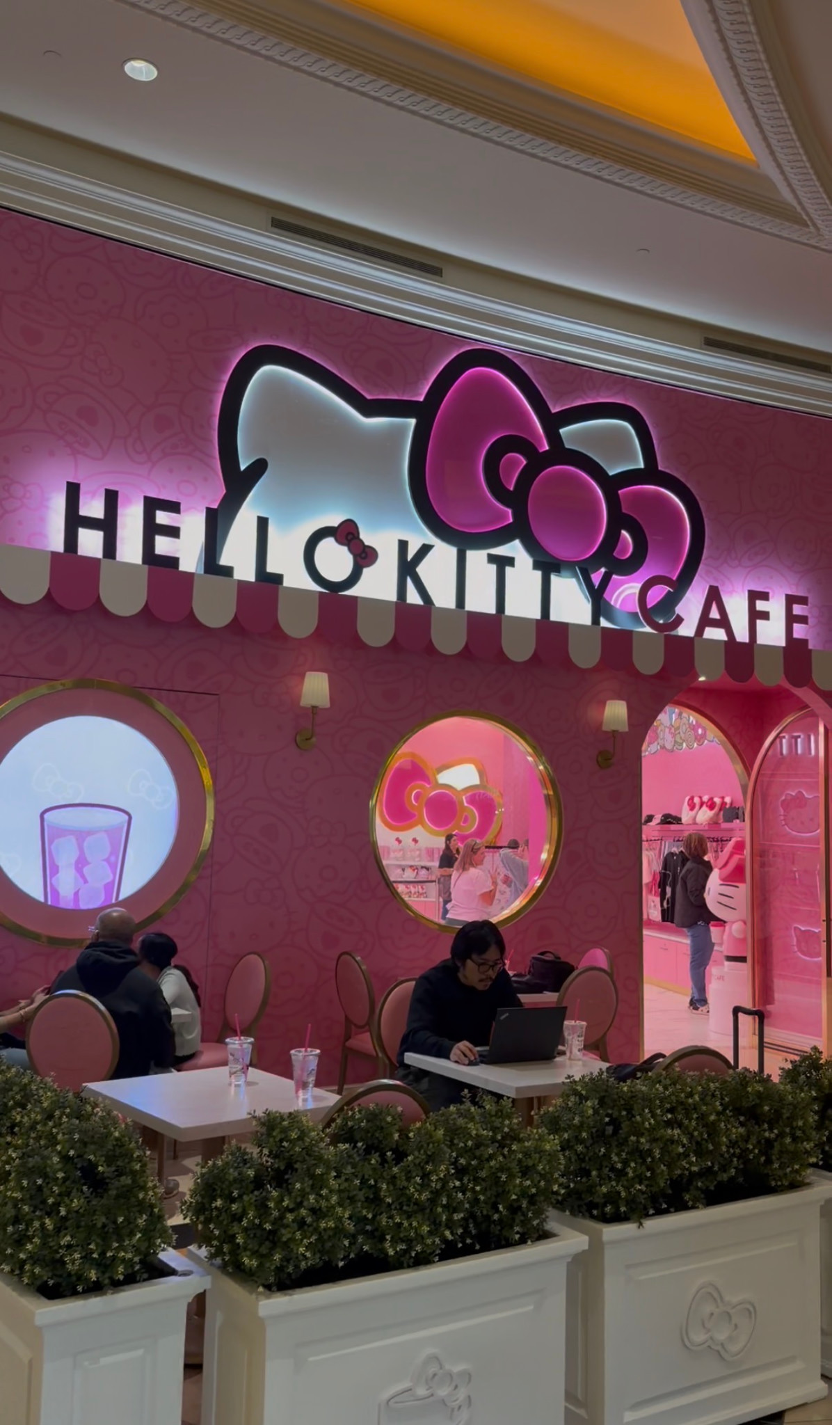 Pink Hello Kitty Cafe storefront with an illuminated character sign and café seating.
