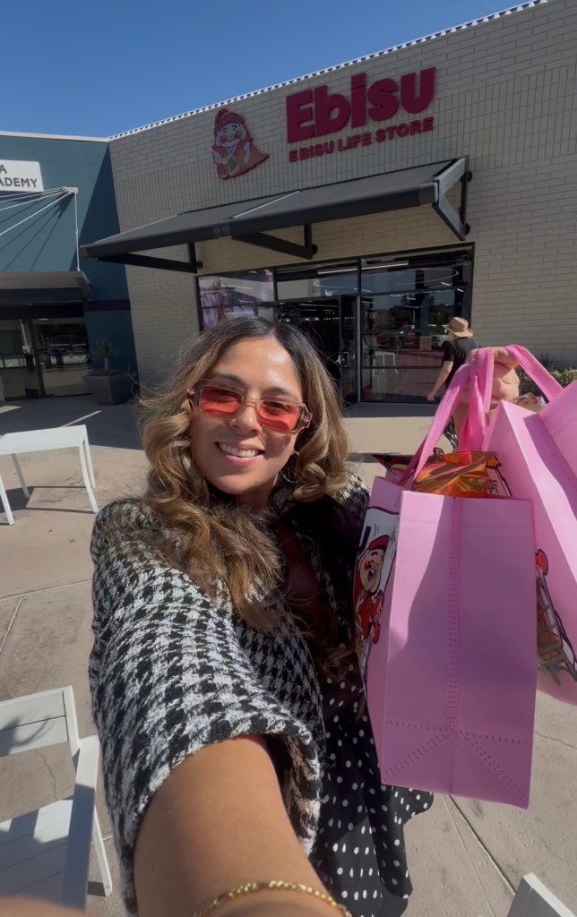 A shopper holds pink EBISU bags outside the EBISU Life Store entrance in La Jolla.