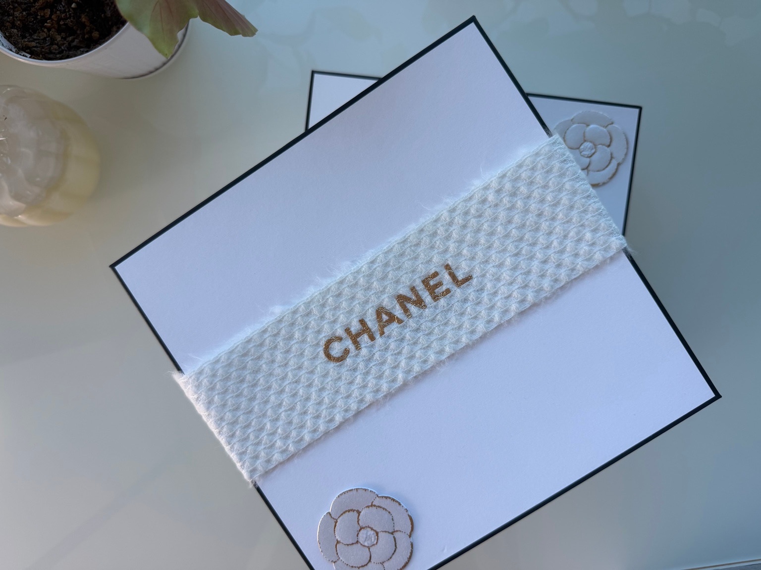 White Chanel gift boxes decorated with a textured white knit band and gold lettering.