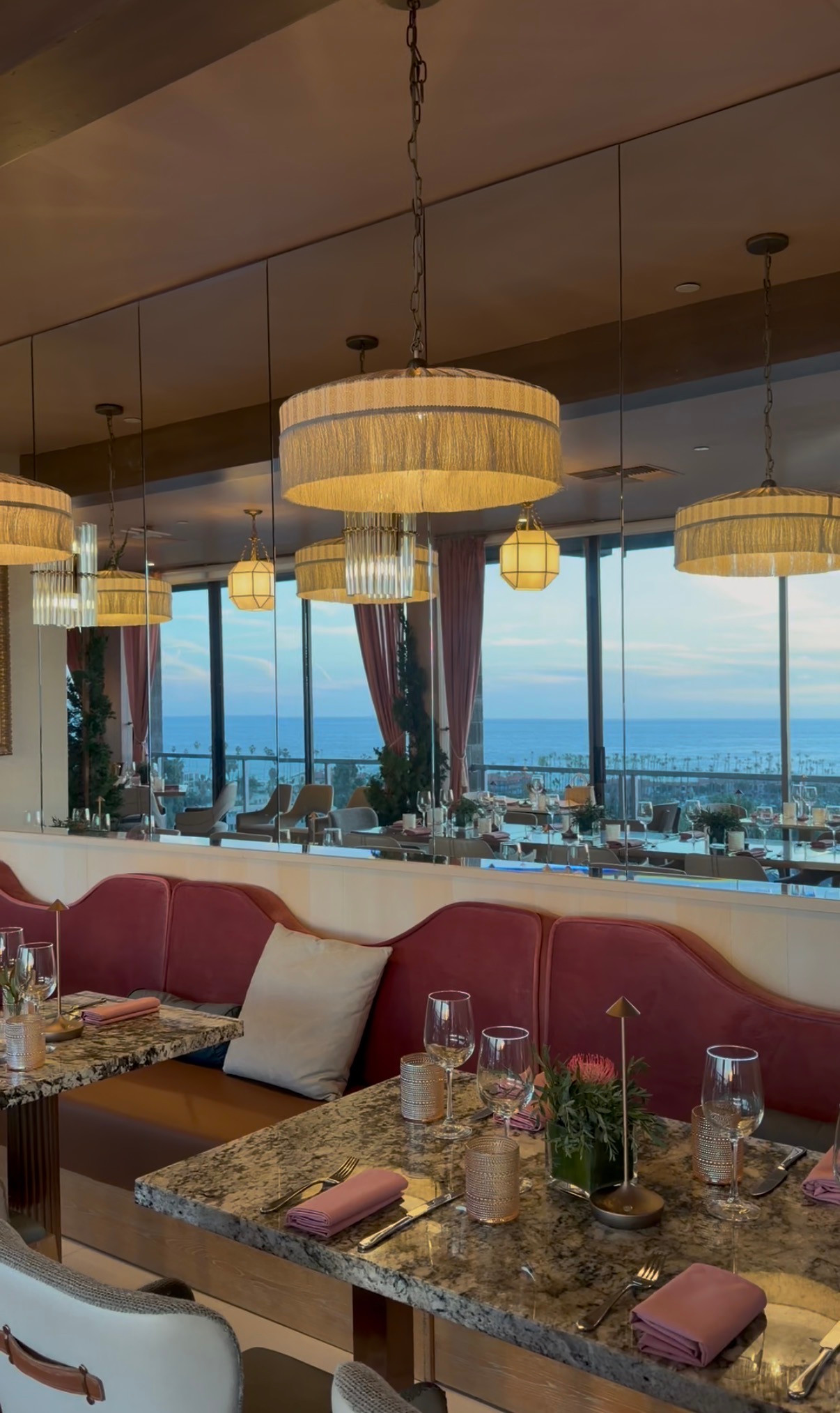 Pink banquette seating and mirrors reflecting the ocean view at Aries La Jolla.