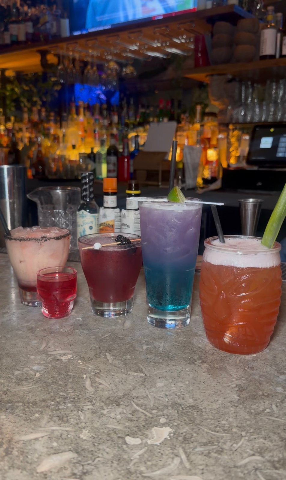 Colorful cocktails and a red skull-shaped shot glass lined up on the bar at Lost Temple Tavern.