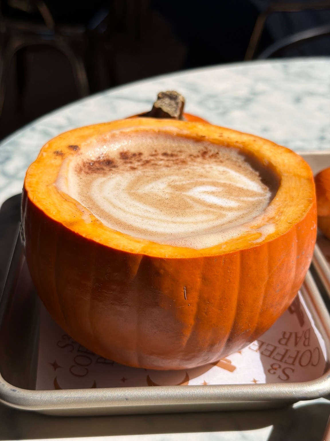Coffee with swirled foam served inside a hollowed orange pumpkin at S3 Coffee Bar.