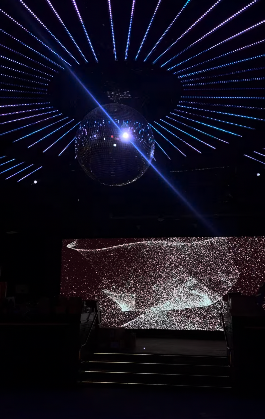 A disco ball and radiating ceiling lights above The Quin's LED stage.