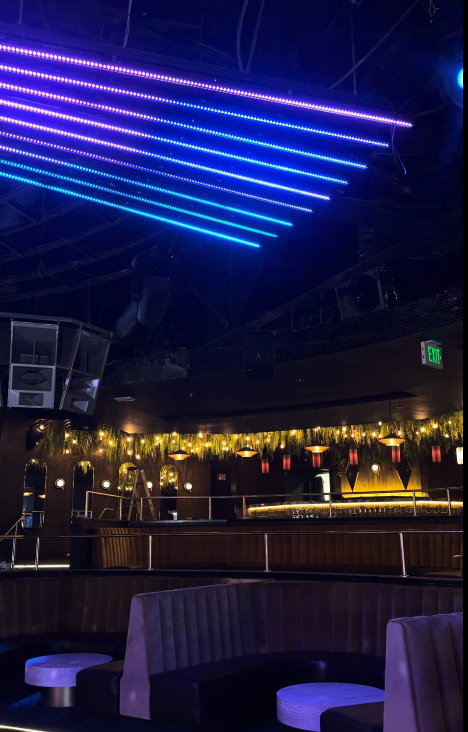 Blue and purple ceiling lights above lounge booths and a warm-lit bar at The Quin.