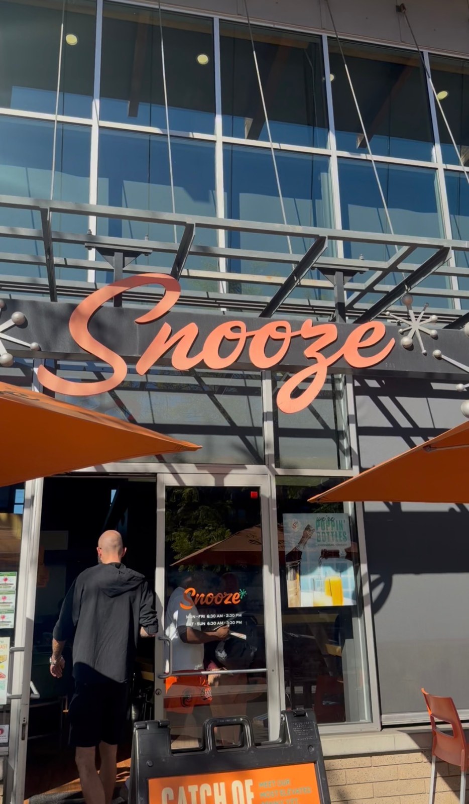 Orange Snooze lettering above the restaurant entrance, with orange patio umbrellas.